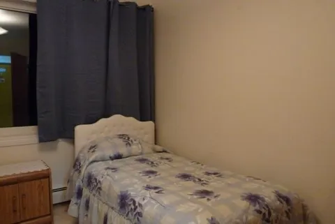 Bedroom with a single bed and dark window curtains.