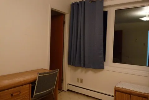 Bedroom desk and chair beside a curtained window.