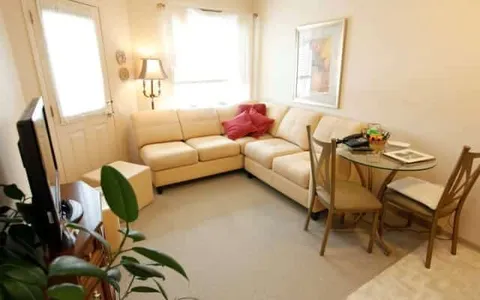 Room with a cream corner sofa, dining table, chairs and tall windows