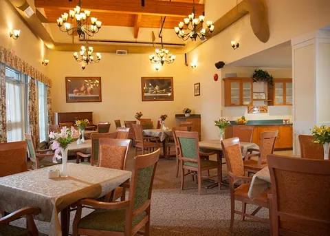 Dining room with tables, upholstered chairs and ceiling chandeliers.