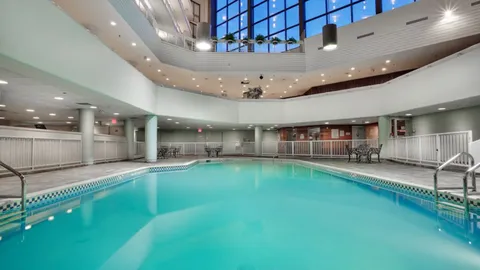 Indoor swimming pool in a high atrium with glass walls.