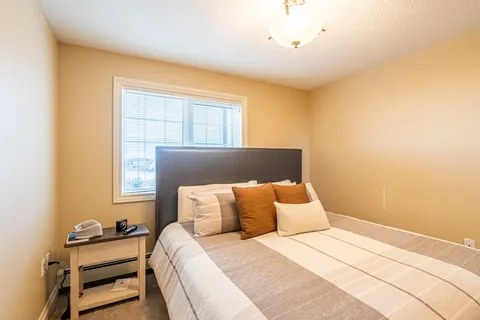 Bedroom with a double bed, pillows, bedside table and window blinds