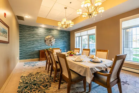 Dining room with a long set table, upholstered chairs and chandeliers