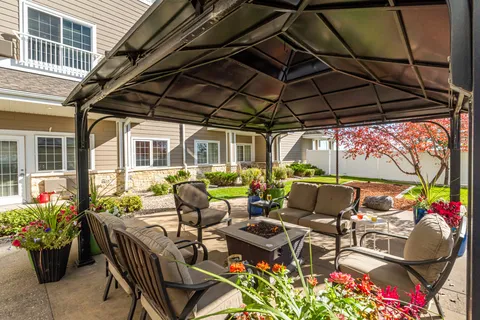 Patio with cushioned seating beneath a gazebo, planters and a garden
