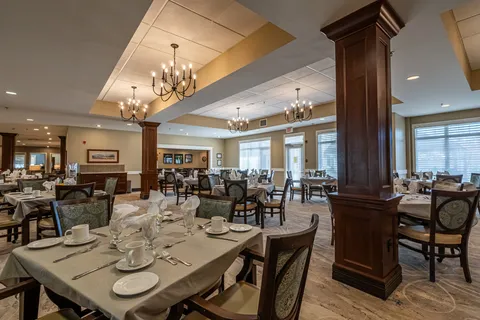 Dining room with set tables, upholstered chairs, wooden columns and chandeliers