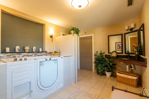 Bathing room with an accessible tub, sink, mirrors and plants