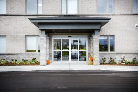 Covered glass entrance with brick walls and garden beds