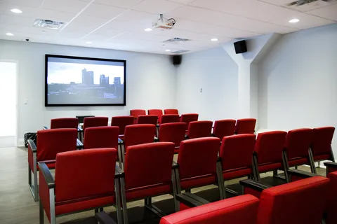 Screening room with red seats, a projector and a screen showing a city view