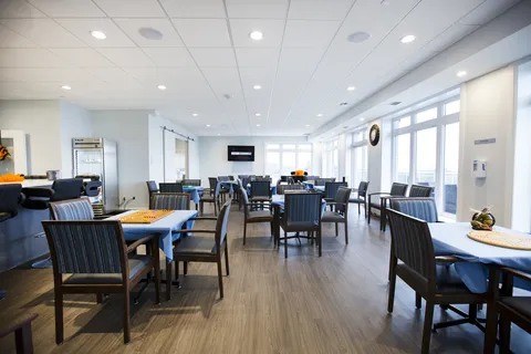 Dining room with tables, upholstered chairs and a wall of windows