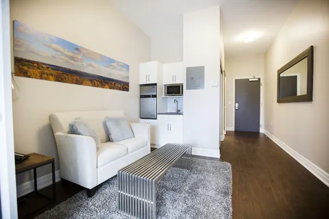 Sitting area with a white sofa, striped bench and a kitchenette