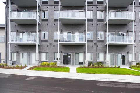 Residence facade with balconies and glass doors beside a landscaped strip