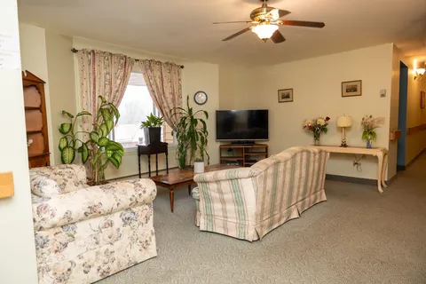 Sitting room with floral sofas beside large windows.