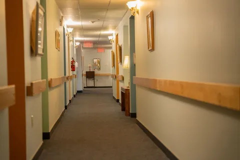 Carpeted corridor with handrails and framed pictures.