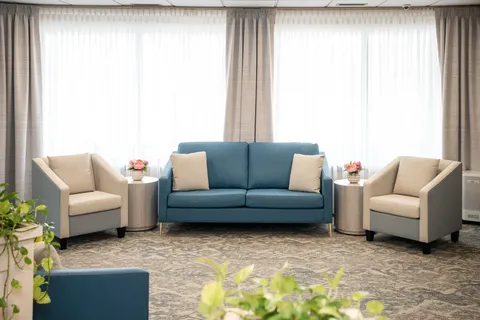 Lounge with blue sofa, armchairs and large curtained windows.
