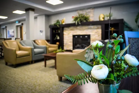 Sitting area with armchairs, a stone fireplace and flowers in the foreground