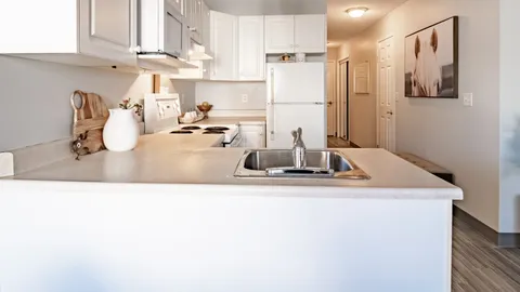 Kitchen with white cabinets, a refrigerator, stove and peninsula counter