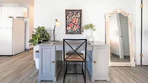 Writing desk and black chair beside a tall mirror