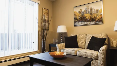 Room with a patterned sofa, dark coffee table and framed cityscape