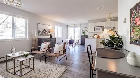 Apartment with wicker chairs, a writing desk, dining table and white kitchen