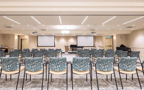 Large room with rows of chairs, tables and two blank projection screens