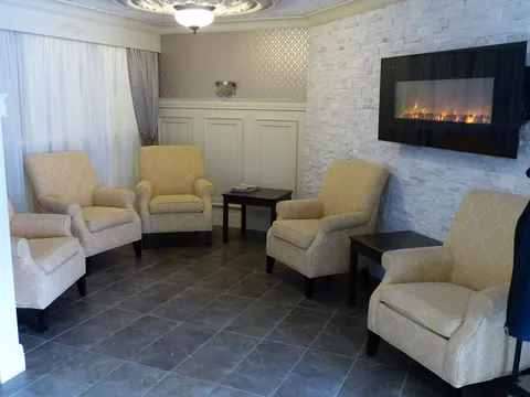 Sitting room with armchairs and a wall-mounted electric fireplace.