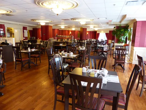 Dining room with wooden tables, chairs and red curtains.