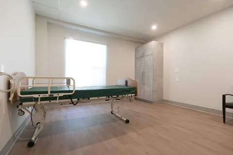Unfurnished suite with an adjustable bed, wardrobe and window.