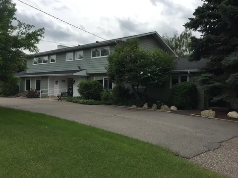 Madison Manor building beside a paved drive, lawn, trees and shrubs.