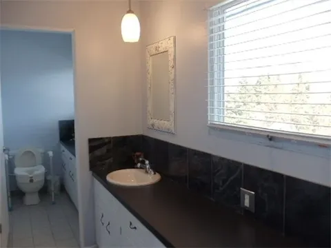 Bathroom with a long counter, sink, mirrors and a window.