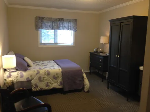 Bedroom with a single bed, dark wardrobe, drawers and a window.