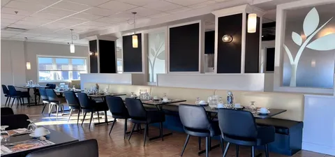 Dining room with dark chairs, set tables and upholstered bench seating