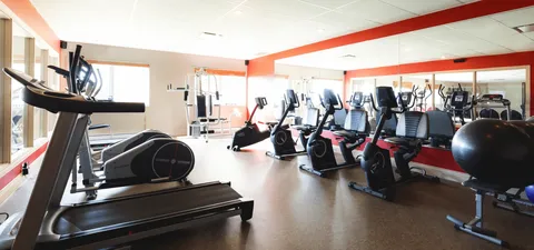 Fitness room with exercise bikes, a treadmill and a mirrored wall