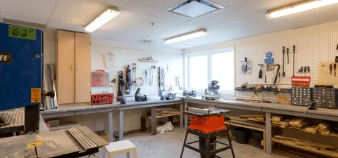 Workshop with workbenches, saws and tools hanging on pegboards
