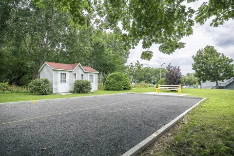 Outdoor petanque court beside trees and a small shed.