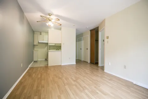 Unfurnished suite living area with a kitchenette and wood flooring.