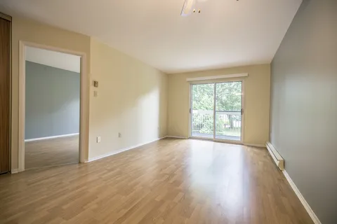 Unfurnished apartment with wood flooring and a large window.