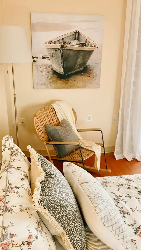 Suite sitting area with a floral sofa, wicker chair and boat artwork.