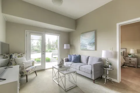 Living room with a sofa, armchair, glass coffee table and patio doors.