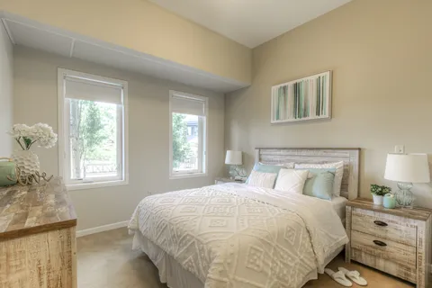 Bedroom with a double bed, bedside tables and two windows.