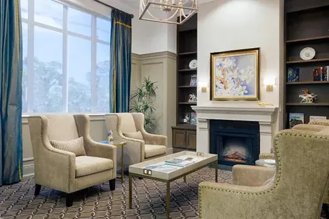 Lounge seating beside a fireplace and tall windows.