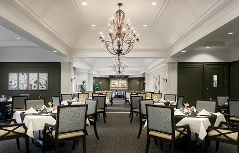 Dining room with rows of set tables and chandeliers.