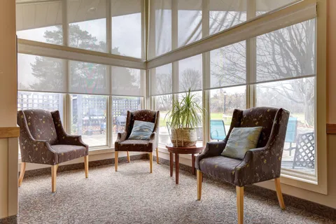 Armchairs beside large windows and a round table