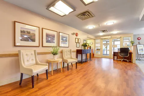 Lobby with pale chairs, wooden flooring, glass doors and an upright piano