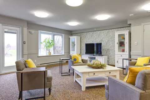 Room with armchairs, a coffee table, television and glass-fronted cupboards