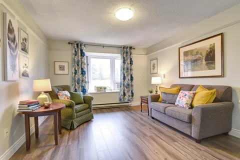Sitting area with a grey sofa, green armchair and window