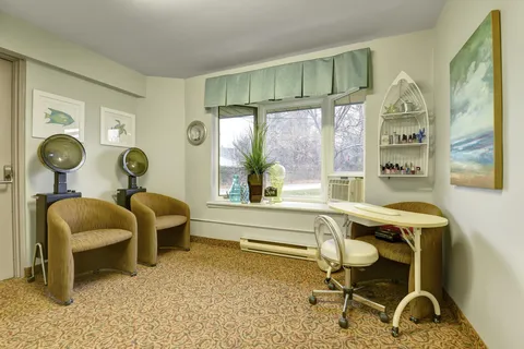 Salon with two hooded dryers, chairs, a mirror and window
