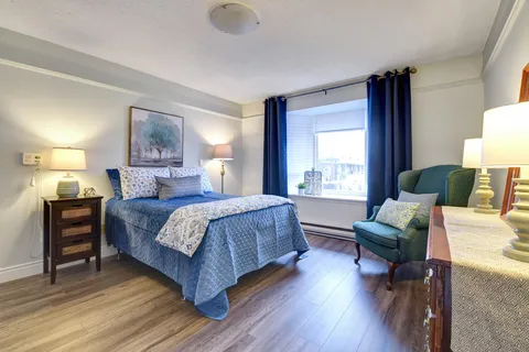 Bedroom with a blue bedspread, green armchair and tall window