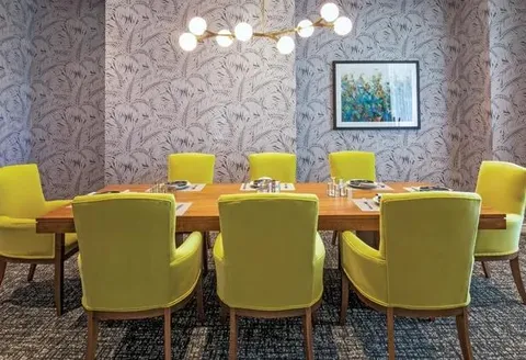 Private dining room with a long table and green chairs.