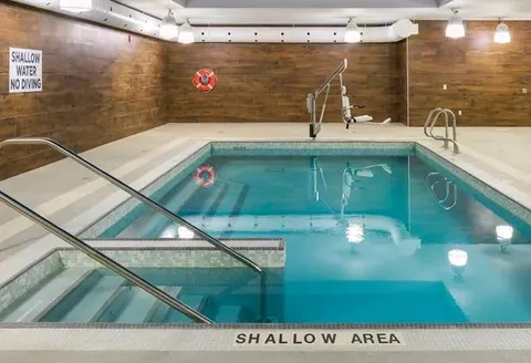 Indoor pool with entry rails and a tiled surround.