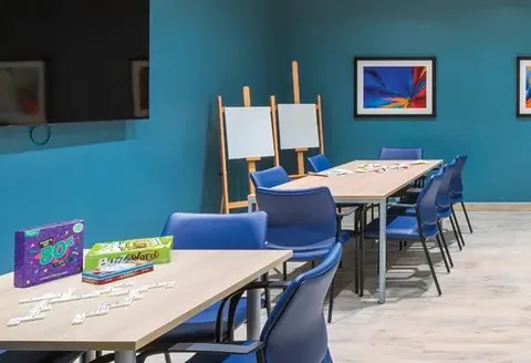 Activity room with tables, chairs, board games and an easel.